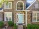 Close-up of a brick home featuring a light blue front door, classic shutters, and manicured landscaping at 4295 Cami Way, Buford, GA 30519