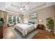 Staged main bedroom featuring tray ceiling, hardwood floors, modern ceiling fan, natural light and sitting area at 4295 Cami Way, Buford, GA 30519