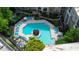 An aerial shot showcases a uniquely shaped pool surrounded by lounge chairs, lush landscaping, and seating areas at 390 17Th Nw St # 2040, Atlanta, GA 30363