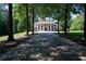 Long driveway leading to a brick home with white columns and a large front lawn, partially shaded by mature trees at 4790 Shallowford Rd, Roswell, GA 30075