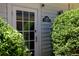 Spa house entrance with glass-paneled door, sign, exterior light and lush landscaping around the perimeter at 4790 Shallowford Rd, Roswell, GA 30075