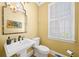 Well-lit powder room with pedestal sink, window with shutters, and decorative mirror and lighting at 2324 Littlebrooke Ln, Dunwoody, GA 30338