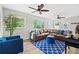 Bright living room features a leather sofa, ceiling fans, and large windows overlooking the lush outdoors at 1143 Mcgarity Rd, Mcdonough, GA 30252
