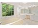 Bright bathroom with a soaking tub under a large window and dual vanities under large mirrors at 2682 Varner Dr, Atlanta, GA 30345