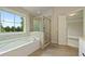 Bright bathroom with a soaking tub, glass-enclosed shower, and large window offering scenic views at 4650 Pleasant Woods Dr, Cumming, GA 30028
