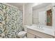 Bright bathroom with a leaf patterned shower curtain, white vanity and a large mirror above the sink at 1917 Oak Grove Ne Rd, Atlanta, GA 30345