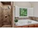 Bathroom featuring a soaking tub, walk-in shower, tiled walls, and plantation shutters at 1917 Oak Grove Ne Rd, Atlanta, GA 30345