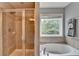 Bathroom with a tiled shower, soaking tub, and large window at 450 Hilingdon Way, Suwanee, GA 30024