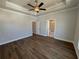 Spacious primary bedroom with a tray ceiling, ceiling fan, hardwood flooring, and ensuite bathroom at 157 Basil St, Cumming, GA 30040