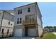 Three-story home featuring a two-car garage, covered balcony, and fenced yard at 157 Basil St, Cumming, GA 30040