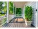 Inviting covered front porch with a dark stained floor, a neutral rug, and a potted evergreen at 940 Longley Nw Ave, Atlanta, GA 30318