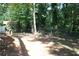 Fenced backyard featuring a mix of dirt and tree cover with mature trees at 5561 Petite Pt, Lithonia, GA 30058