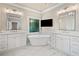 Luxurious bathroom with a modern tub, a TV, dual sinks, and white marble floors at 997 Thousand Oaks Nw Bnd, Kennesaw, GA 30152