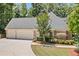View of a brick home with a three car garage and mature landscaping at 997 Thousand Oaks Nw Bnd, Kennesaw, GA 30152
