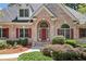 Close up of a beautiful brick home featuring lush landscaping and a red front door at 997 Thousand Oaks Nw Bnd, Kennesaw, GA 30152