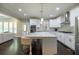 Open kitchen with island seating, stainless appliances, and stylish lighting fixtures at 3589 Tamerton Trce, Buford, GA 30519