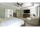 Bright, spacious main bedroom with a tray ceiling, neutral colors, large TV, and a sitting area by the windows at 3589 Tamerton Trce, Buford, GA 30519