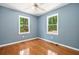 Sunny bedroom with hardwood floors, ceiling fan, and two windows that let in natural light at 4614 Ridge Dr, Pine Lake, GA 30072