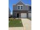 Charming two-story townhome featuring brick accents, a one-car garage, and freshly manicured landscaping at 312 Naples Way, Locust Grove, GA 30248