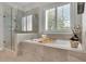 Luxurious bathroom with a soaking tub, glass shower, and plantation shutters at 3330 Riverwalk Way, Cumming, GA 30040