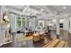 Open-concept living room boasts coffered ceilings, a large window array and seamless flow to the modern kitchen at 3330 Riverwalk Way, Cumming, GA 30040