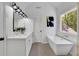 Bright bathroom featuring double vanity, freestanding tub, large window, and modern fixtures at 4999 Willow Creek Dr, Woodstock, GA 30188