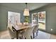Bright dining room with paneled walls, a modern light fixture, a wood table, and serene outdoor views at 4999 Willow Creek Dr, Woodstock, GA 30188