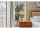 Bedroom detail showing a nightstand, lamp, and view of the landscaped yard at 1027 Riverbend Club Se Dr, Atlanta, GA 30339