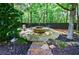 A stone fire pit sitting area with chairs surrounded by mature trees and lush landscaping at 2101 Hunters Green Dr, Lawrenceville, GA 30043
