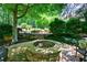 Stone fire pit seating area with mature landscaping, plants, and mature trees at 2101 Hunters Green Dr, Lawrenceville, GA 30043