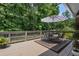 Back deck with wooded view perfect for entertaining and a table with a striped umbrella at 290 Dania Dr, Alpharetta, GA 30009