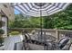 Back deck with a table, chairs, and a striped umbrella in a backyard with a wooded view at 290 Dania Dr, Alpharetta, GA 30009