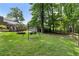 Backyard featuring a fire pit, swing, back deck, manicured lawn, and a border of trees at 290 Dania Dr, Alpharetta, GA 30009