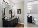 Bathroom features a vanity, arched mirrors, toilet, and decorative artwork on the wall at 290 Dania Dr, Alpharetta, GA 30009
