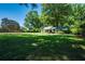 Spacious green yard and a charming single-story home nestled amongst mature trees on a sunny day at 290 Dania Dr, Alpharetta, GA 30009