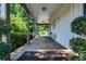 Covered side porch with brick flooring, offering a serene outdoor seating area surrounded by greenery at 290 Dania Dr, Alpharetta, GA 30009