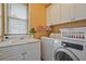 Cozy laundry room with white cabinetry, a sink, and a modern front load washing machine at 6477 Blue Water Dr, Buford, GA 30518