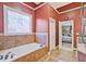 Bathroom featuring a large soaking tub with tile surround and a frosted glass window for privacy at 6477 Blue Water Dr, Buford, GA 30518
