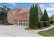Side view of a three-car garage with a brick exterior and trimmed evergreen bushes at 910 Ovalene Sw Ln, Marietta, GA 30064