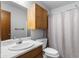 Bathroom features wood cabinets, neutral walls, a standard white sink, toilet, and shower curtain at 1757 Mystery Sw Cir, Conyers, GA 30094