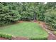 Lush backyard showcasing a large lawn, mature trees, and serene seating area at 3323 Lancing Ct, Duluth, GA 30096