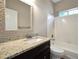 Bathroom with a granite countertop, framed mirror, and tub-shower combination at 5600 Walnut Creek Nw Ct, Lilburn, GA 30047