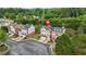 An aerial view shows this townhome with brick facade and red shutters, nestled in a green community with mature trees at 5989 Turfway Park Ct, Sugar Hill, GA 30518