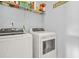 Laundry room equipped with a white washer and dryer with a storage shelf above at 5989 Turfway Park Ct, Sugar Hill, GA 30518