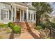 Inviting front porch with brick steps, white columns, and iron railings amidst lush greenery at 735 Longwood Nw Dr, Atlanta, GA 30305