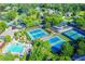 Aerial view of community amenities featuring a pool, tennis courts, and clubhouse surrounded by lush trees and parking at 5675 Habersham Vly, Suwanee, GA 30024