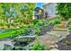 Multi-tiered backyard with a rock waterfall and lush landscaping leading up to a screened porch with an external staircase at 5675 Habersham Vly, Suwanee, GA 30024