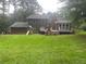 A view of the back exterior showcasing the deck, screened porch, and a large yard with playset at 710 Wind Song Trce, Woodstock, GA 30189