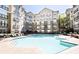 Exterior view of a community swimming pool surrounded by lounge chairs and apartment building at 800 Peachtree Ne St # 1319, Atlanta, GA 30308