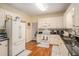 Charming kitchen with white cabinetry, black countertops, and hardwood floors throughout the space at 1644 Beaver Creek Ln, Snellville, GA 30078